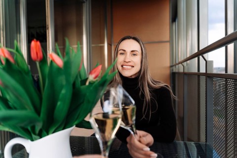 Young woman checking with boyfriend while sitting at table with bouquet of flowers on date, A woman