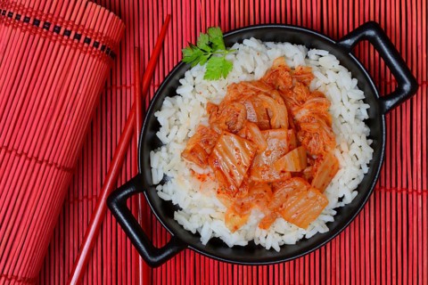Kimchi, fermented vegetables on rice in bowl with chopsticks