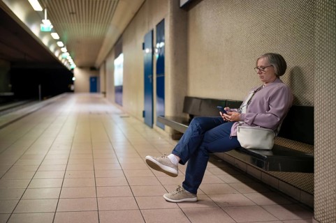 Elderly woman sitting on bench, lonely, alone, waiting in Maybachstraße subway station for light