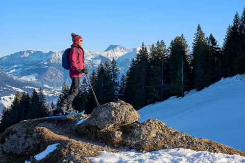 Nice and active senior woman snowshoeing in in the snow covered Allgaue alps above the valley of