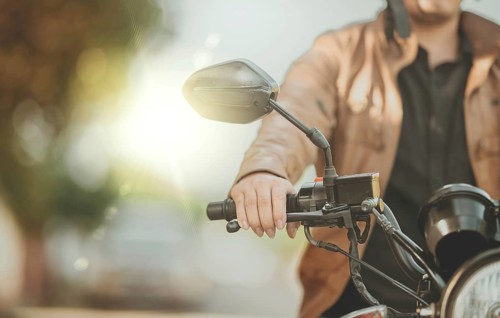 Close up of hands of biker on the handlebars of a motorcycle outdoors. Hands of motorcyclist on the