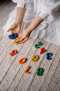 Hands sorting colorful numbers on the floor, displaying a playful learning activity