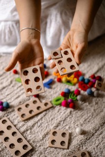 Hands holding wooden counting toys with colorful balls scattered around