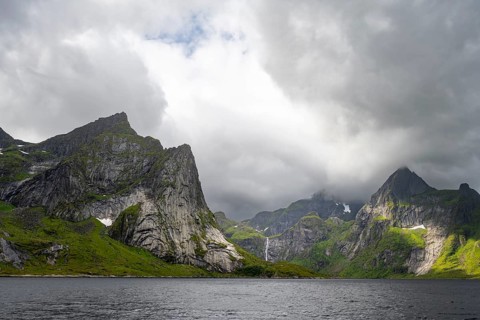 Waterfall and fjord landscape with mountains, Reinefjord, Lofoten, Norway