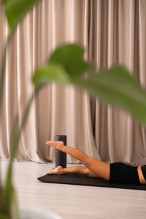 Feet elevated on foam roller and curtains in background, conveying a relaxed yoga practice