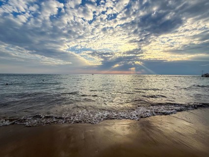 Coastal scene at sunset, waves gently hitting the sand under a cloudy sky, Side, Manavgat, Antalya