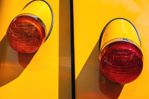 Chrome-rimmed twin round tail lights on a yellow classic car at a car meet