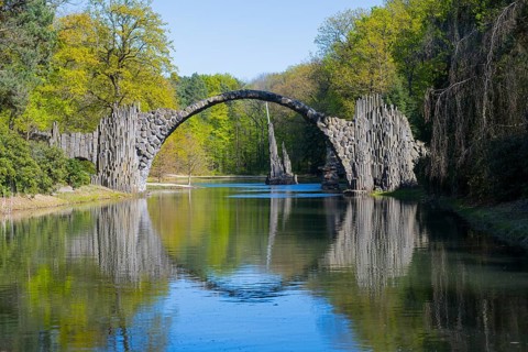 Stone bridge with perfect reflection in water surrounded by lush greenery, Rakotz Bridge, Devil's