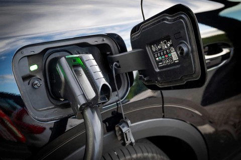Fully electric Ford Explorer is being charged, charging cable in electric tank, charging station