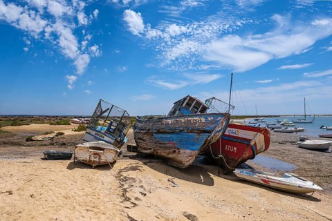 Old abandoned boats are lying on a beach under a slightly cloudy sky, Santa Luzia, Tavira, Faro,