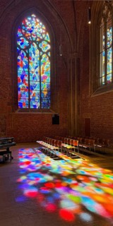 Stained glass window by Alfred Manessier with colorful light spots on the floor in the City Church
