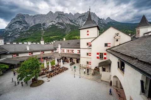 Castle with courtyard, mountain peaks of the Tennengebirge Mountains at the back, dramatic clouds,