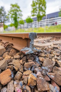 Warped railway track on a gravel bed, shows damage and has an uneven surface, station conversion