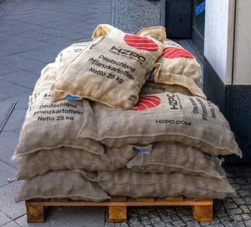 Jute bags stacked on a wooden pallet with the inscription Seed Potatoes Netto 25 kg, Berlin,