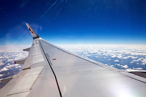 View from an airplane window with a view of the wing and many clouds under a blue sky, aircraft