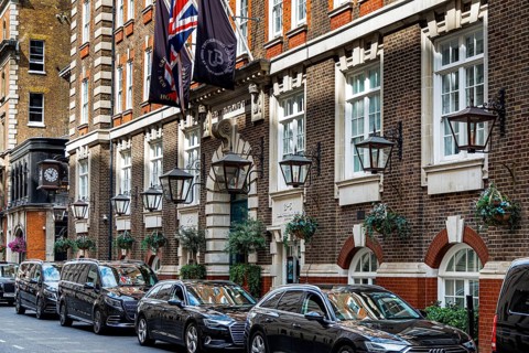Black cars are parked along the brick and stone facade of the Great Scotland Yard Hotel in