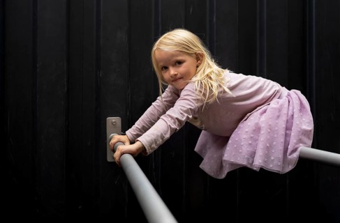 Girl, blonde, 5 years old, dress, gymnastics on climbing pole, climbing frame, smiles, playground,