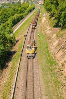 Vehicle and workers seen on a sunny train line in green surroundings, Leonhard Weiss construction