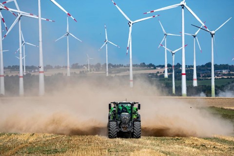 Tractor with mineral fertilizer spreader, cultivates a harvested grain field, spreads mineral