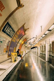Underground platform of a subway station with a vaulted, white-tiled ceiling, large advertising