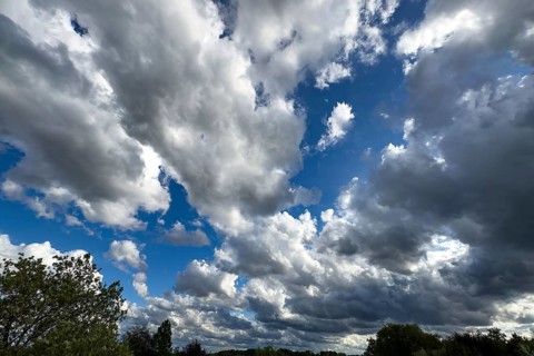 Large cloud field of dark cumulus cluster clouds at the bottom announce rain clouds rain front on