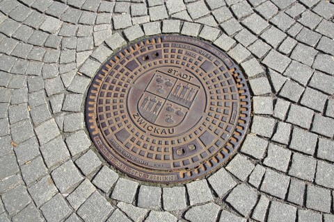 Round manhole cover with city coat of arms and inscription, paving stones, Zentrum station,