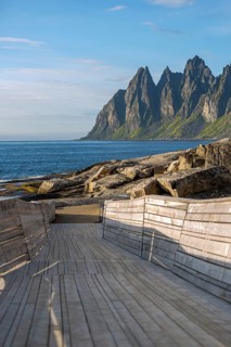Modern wooden walkway leads to the rocky coast of Tungeneset in front of the distinctive Devil's