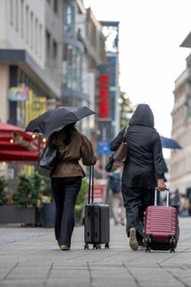 Passers-by in downtown Essen, pedestrian zone, rainy weather, trolley, on the way to the main train