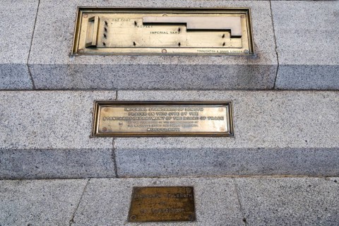 Brass plaques recording the Imperial Standards of Length are set into the granite steps at the wall