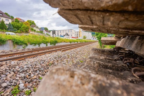 View along the railway tracks with focus on gravel and city buildings, station conversion