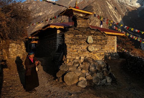 Young woman next to a small Buddhist monastery with manistones in the evening light, Nepalese,