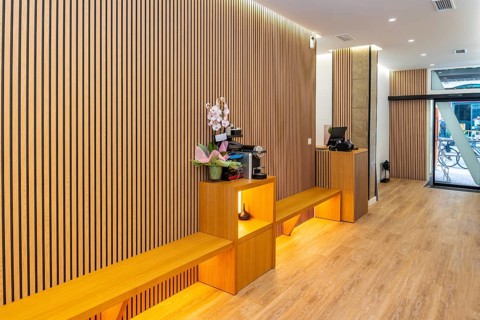 Contemporary aesthetic clinic reception with warm wooden slat wall panels, integrated seating and