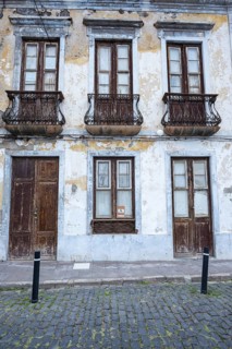 Weathered façade of an empty house in Garachico, characterized by crumbling plaster, old wooden