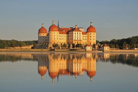 Baroque castle with reflection in the lake, yellow baroque castle with corner towers, lighting