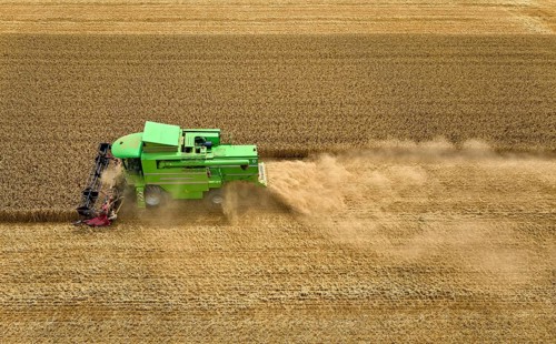 Aireal photo of a combine harvester harvesting wheat on a field in the vertile and fruitful of