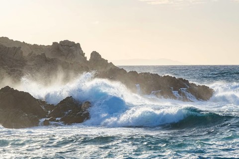 Braking waves at the coastline of Marinedda Coast at sunset, Sardinia, Italy