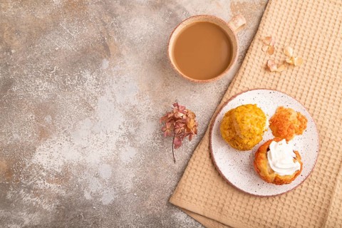 ?houx pastry with cup of coffee on brown concrete background with beige textile, copy space, top