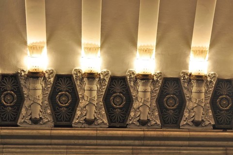 Ornate ceiling decorations and warm lighting create a festive atmosphere in a subway station,