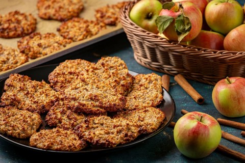 Ready apple cookies on a plate next to a basket of apples