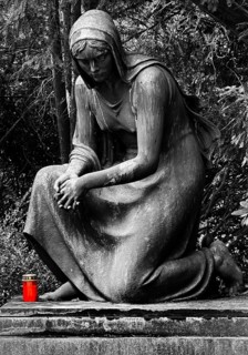 Black and white photo of a tomb with kneeling woman and red grave light with cover, Engesohde City