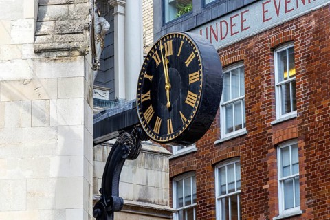 A black and gold clock projects from the tower of St Dunstan-in-the-West on Fleet Street, its