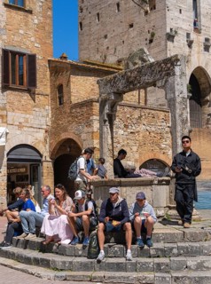 Tourists around the market square with old fountain and other sights in San Gimignano, Tuscany,