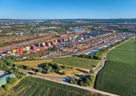 Aerial view of a large container terminal with freight trains, shipping containers, cranes, and