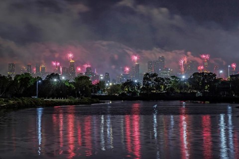 City skyline with fireworks lighting up the night sky, reflections on the river, Fireworks from the