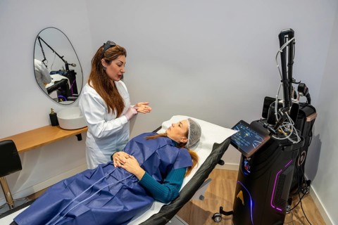 Specialist in protective eyewear explaining laser hair removal procedure to a female client lying