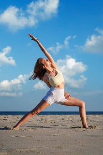 In a half-bound Viparita Virabhadrasana yoga variation, Reverse Warrior, a woman reaches one arm