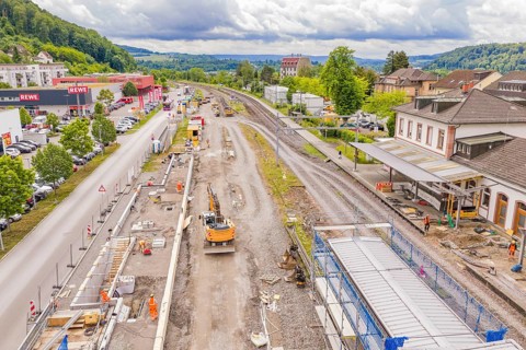 Aerial view of a train station with surrounding area, construction site near tracks and buildings