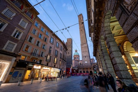 Due Torri Garisenda and Asinelli, landmarks of the city, illuminated Via Rizzoli in the evening,