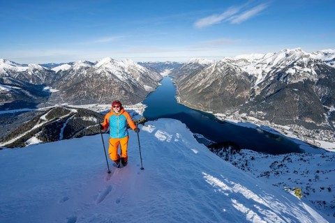 View of Achensee and wintry mountain scenery, ski tourer at the summit of Bärenkopf, Achensee,