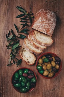 A mixture of olives, varieties of Halkidiki, Verdi giganti and Kalamata, in a bowl, with sliced